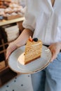 Piece of a russian honey cake on a plate, that woman is holding