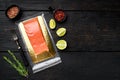 Piece of salmon fillets in a vacuum blister pack, with herbs, on black wooden table background, top view flat lay, with copy space