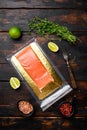 Piece of salmon fillets in a vacuum blister pack, with herbs, on old dark wooden table background, top view flat lay