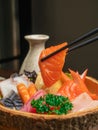 A piece of salmon sushi grab with chopstick over the Chirashi bowl