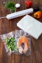 A piece of salmon in a vacuum bag and broccoli next to a pack of vacuum bags