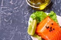 A piece of salmon on a white plate with olives and lemon, on a gray background. Selective focus. space for text.
