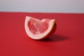 A piece of a slice of red grapefruit on a red background with a hard shadow. Fruit creative benefit red on red Royalty Free Stock Photo