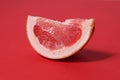 A piece of a slice of red grapefruit on a red background with a hard shadow. Fruit creative benefit red on red Royalty Free Stock Photo