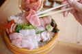 A piece of sliced japanese fish is tong by chopsticks selective
