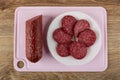 Piece of smoked sausage, slices of sausage in plate on cutting board on table. Top view Royalty Free Stock Photo