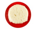 Piece of cheese in polyethylene pack on red saucer isolated on white. Top view