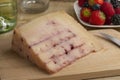 Piece of Spanish goat cheese with red fruit syrup injected on a cutting board