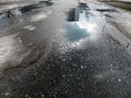 A piece of spring sky, which is reflected in the melted puddle on the asphalt road