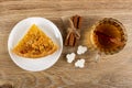 Piece of lemon pie in plate, bunch of cinnamon sticks, sugar cubes, cup of tea on wooden table. Top view