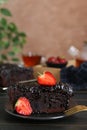 Piece of tasty chocolate sponge cake with strawberries on black table, closeup Royalty Free Stock Photo
