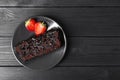 Piece of tasty chocolate sponge cake with strawberries on black wooden table, top view. Space for text Royalty Free Stock Photo