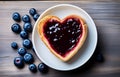 piece of toast bread inside of it cut heart filled with blueberry jam on plate and coffee cup on white wooden table top view Royalty Free Stock Photo