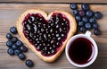 piece of toast bread inside of it cut heart filled with blueberry jam on plate and coffee cup on white wooden table top view Royalty Free Stock Photo