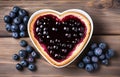 piece of toast bread inside of it cut heart filled with blueberry jam on plate and coffee cup on white wooden table top view Royalty Free Stock Photo