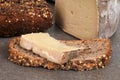 Piece of tomme de Domessin on a slice of seeded bread close-up