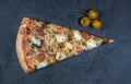 A piece of traditional pizza decorated with a branch of yellow cherry tomatoes on a gray stone background Royalty Free Stock Photo