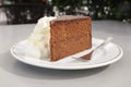 A piece of traditional vienna chocolate cake Sacher with whipped cream on white plate in outdoor cafe Royalty Free Stock Photo