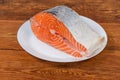 Piece of uncooked salmon on white dish on rustic table Royalty Free Stock Photo