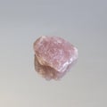 Piece of unpolished pink quartz on white mirror. Minimal color still life Narrow focus line, shallow depth of field Royalty Free Stock Photo