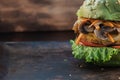 Piece of veggie burger. lettuce, cutlet vegetarian meat alternatives, mushrooms. rusty baking stick. wooden background. copyspace Royalty Free Stock Photo