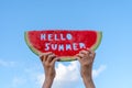 A piece of watermelon against a blue sky. Children`s hands are holding a slice of watermelon with the text Hello Summer. Summer Royalty Free Stock Photo