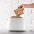 a piece of wheat bread in a toaster. fried toast flies of a white toaster on a white background