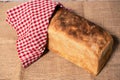 Piece of white bread on a cutting board partially covered with a checkered tea towel. Royalty Free Stock Photo