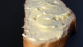 A piece of white bread and butter rotates on a black background