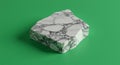 A piece of white marble with prominent gray veining rests on a solid green surface. Royalty Free Stock Photo