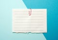 Piece of white paper in a line and a red paper clip on a blue background Royalty Free Stock Photo