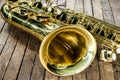 Piece of yellow saxophone - bell and valves on a vintage wooden surface