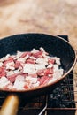 Pieces of bacon in a pan in a forest on a fire - fatty high-calorie dish Royalty Free Stock Photo