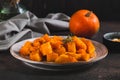 Pieces of baked pumpkin with rosemary on a plate on the table Royalty Free Stock Photo