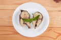 Pieces of baked yellowtail, basil on dish on rustic table