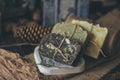 Pieces of beautiful natural handcrafted soap on wooden background with botanical elements, close up view.