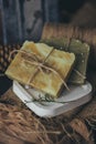 Pieces of beautiful natural handcrafted soap on wooden background with botanical elements, close up view.