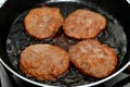 pieces of beef burger being fried on shallow oil on a frying pan, meat burgers cutlet shaped patty made of minced meat Royalty Free Stock Photo