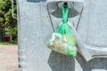 Pieces of bread in the plastic or nylon bag left on the metal garbage dumpster can on the street in the city for poor hungry or ho