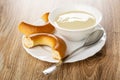 Pieces of bread rings baranka, spoon, bowl with condensed milk in plate on table Royalty Free Stock Photo