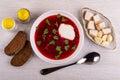 Bread, salt, pepper, borscht with parsley, sour cream in plate, garlic, salted lard, spoon on table. Top view Royalty Free Stock Photo