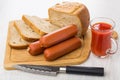 Pieces of bread, sausages on cutting board, knife, tomato juice Royalty Free Stock Photo