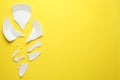 Pieces of broken ceramic plate on yellow background, flat lay. Space for text Royalty Free Stock Photo