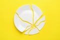 Pieces of broken ceramic plate on yellow background, flat lay Royalty Free Stock Photo