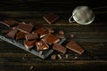 Pieces of broken dark chocolate on a black kitchen table and a kitchen strainer for chocolate chips. Dessert cooking concept Royalty Free Stock Photo