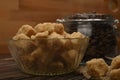 Pieces of brown sugar in a sugar bowl and coffee beans in a glass jar on a wooden background. Close up Royalty Free Stock Photo