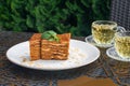 Pieces of cake and two glass cups of mint tea. Medovik cake on a table in a summer cafe. Tea drinking concept, Russian culture. Royalty Free Stock Photo