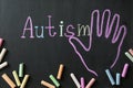 Pieces of chalk on blackboard with word Autism and drawn palm, flat lay Royalty Free Stock Photo