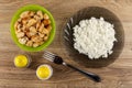 Pieces of chicken meat in bowl, boiled rice in gray plate, salt and pepper, fork on wooden table. Top view Royalty Free Stock Photo