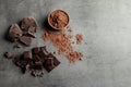 Pieces of chocolate and cocoa powder on grey background Royalty Free Stock Photo